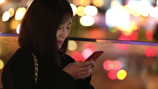 一个女人晚上在城市街道户外使用手机视频素材