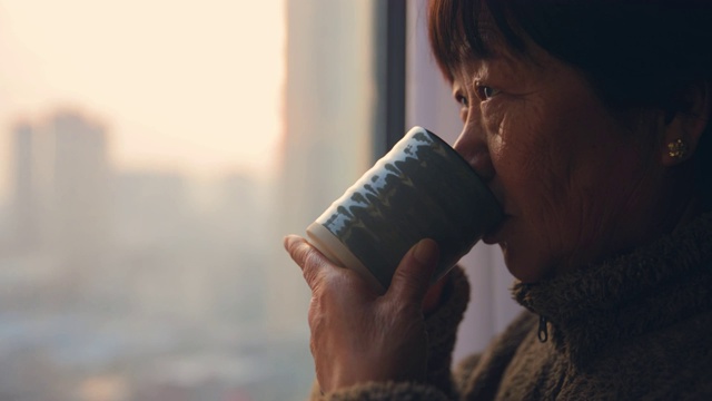 老年人站在窗户边喝一杯咖啡或者茶视频素材