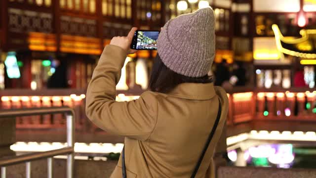 夜晚在上海豫园用手机拍照的女人视频素材