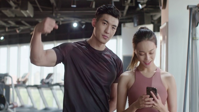 年轻在健身房使用手机自拍视频下载