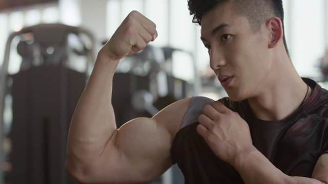 年轻男士在健身房展示肌肉视频下载