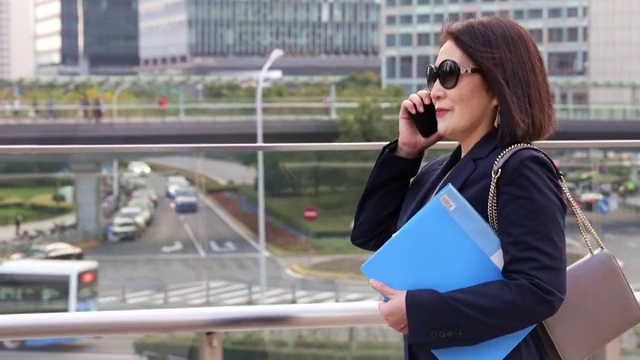 商务女士在城市CBD户外使用智能手机打电话视频素材