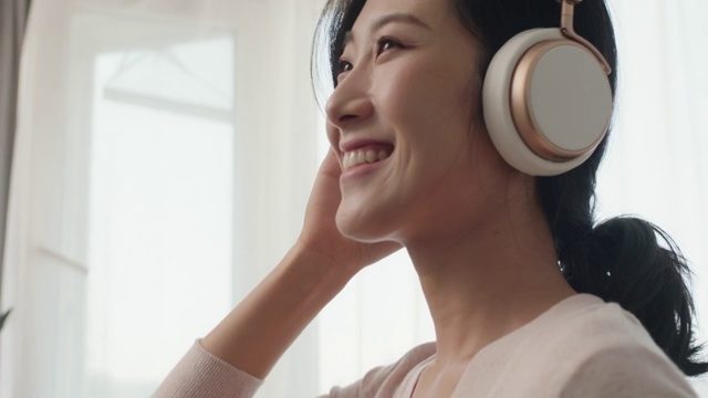 快乐年轻女士在家戴着耳机听音乐视频素材