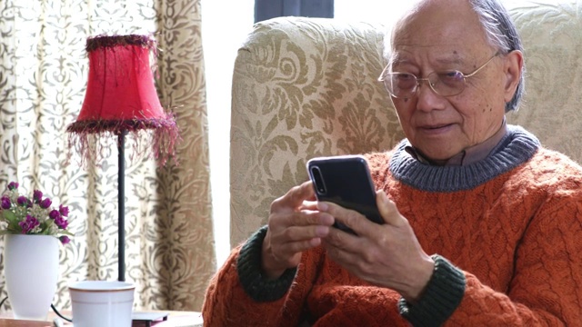 老年男人在家里看手机视频素材
