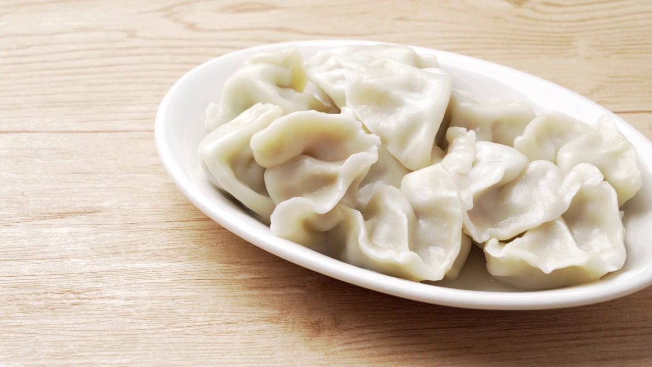 中国传统节日家里的味道低调清新木色背景上的一碟饺子和肉馅视频素材