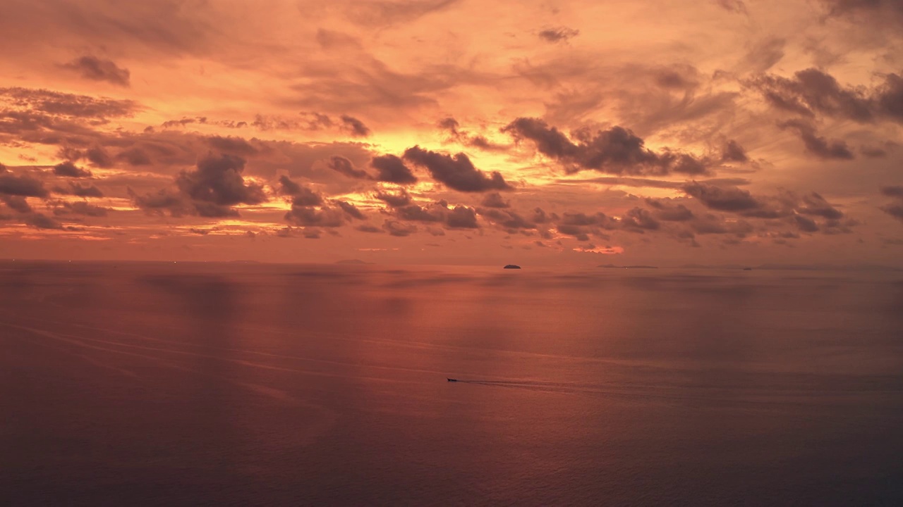 航拍夕阳晚霞红色海面驶过一艘小船视频素材