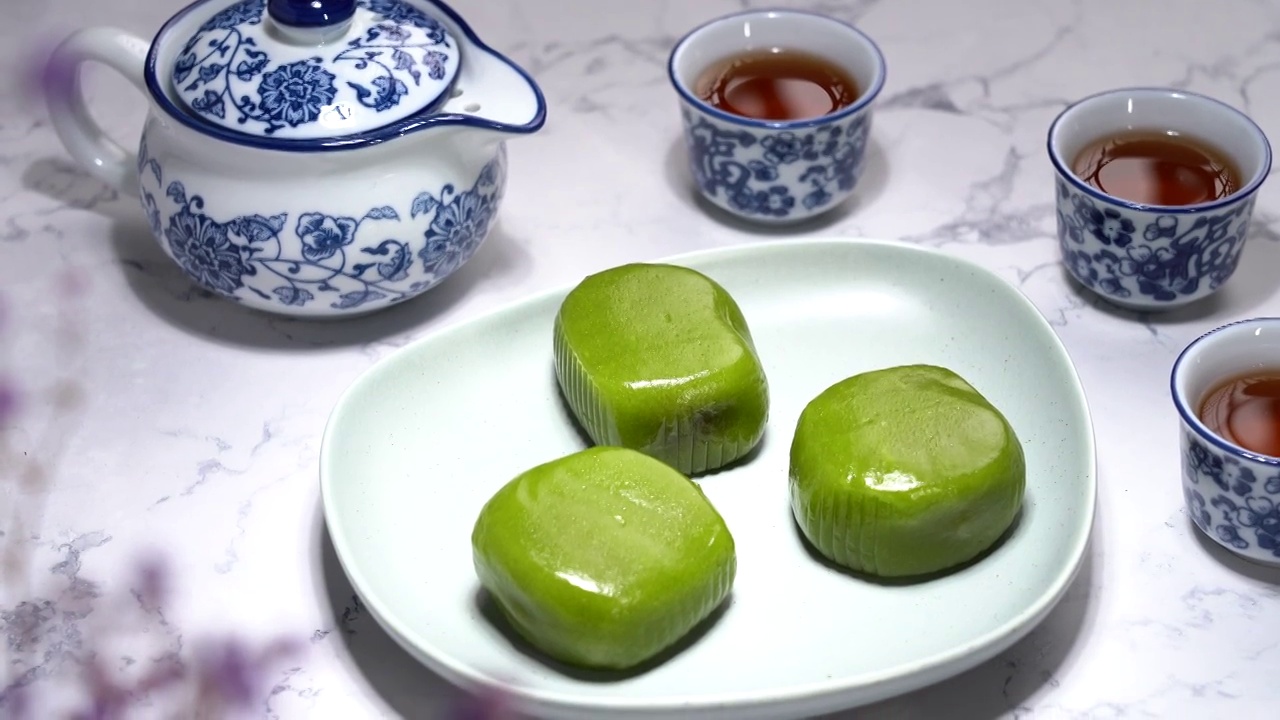 中国元素立春地道传统甜品盘子上的青团艾糍饼和青花瓷器茶水视频素材