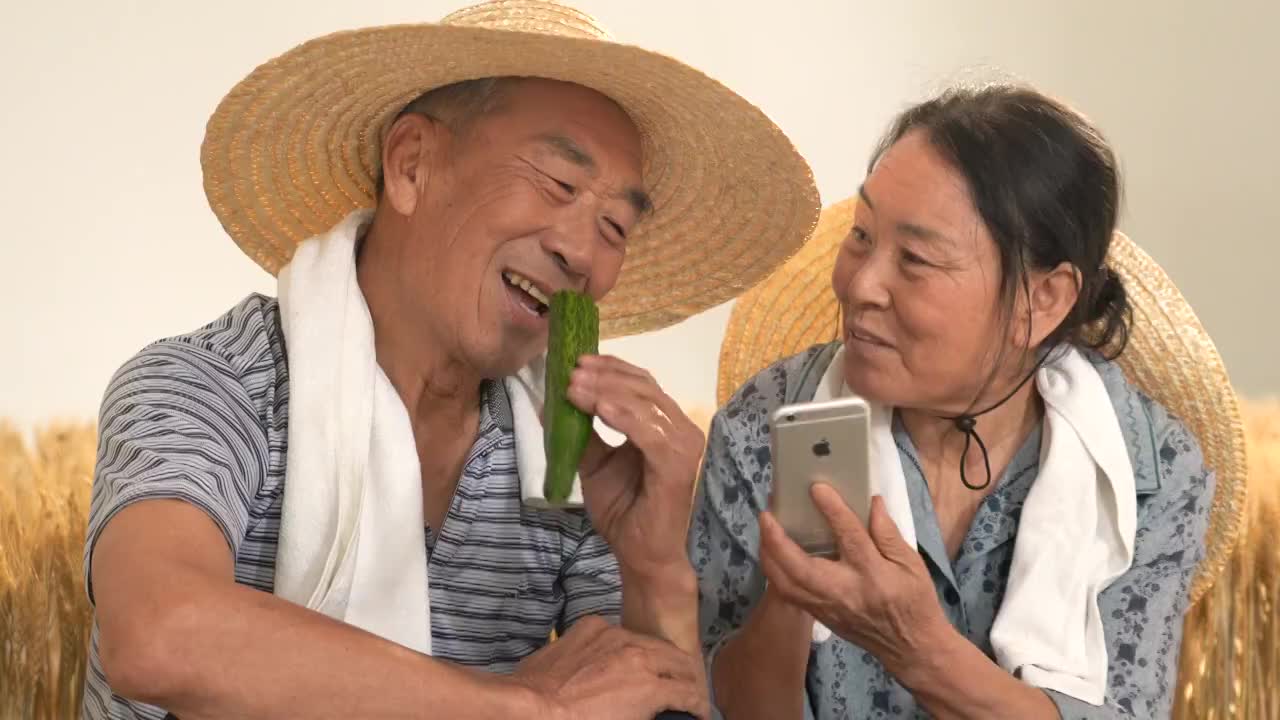 老年夫妇在麦田使用手机通讯视频购买