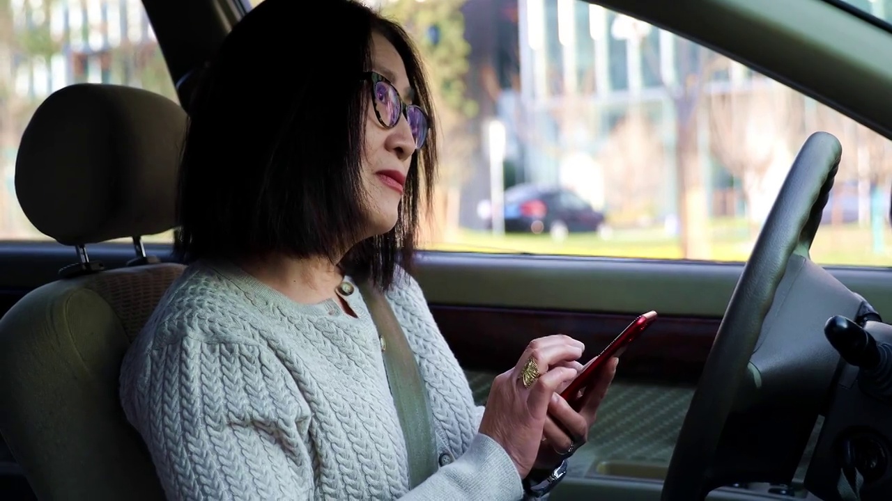 一个女人坐在汽车内使用智能手机APP导航视频下载