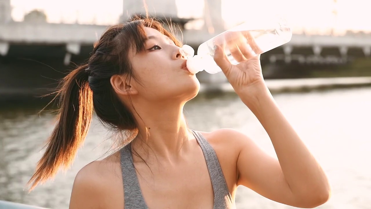 年轻女性在户外健身，喝水视频下载