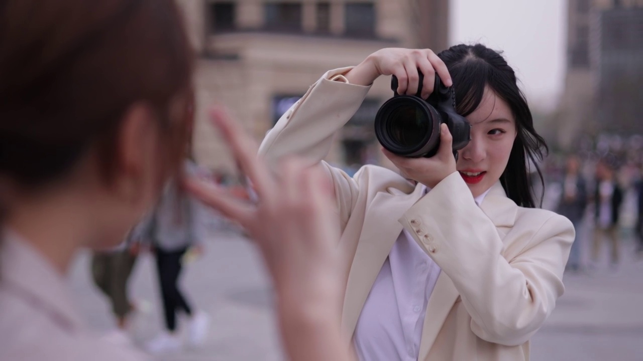 年轻的女摄影师在街头拍摄人像视频素材
