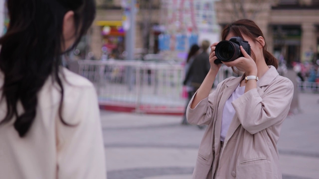 年轻的女摄影师在街头拍摄人像视频素材