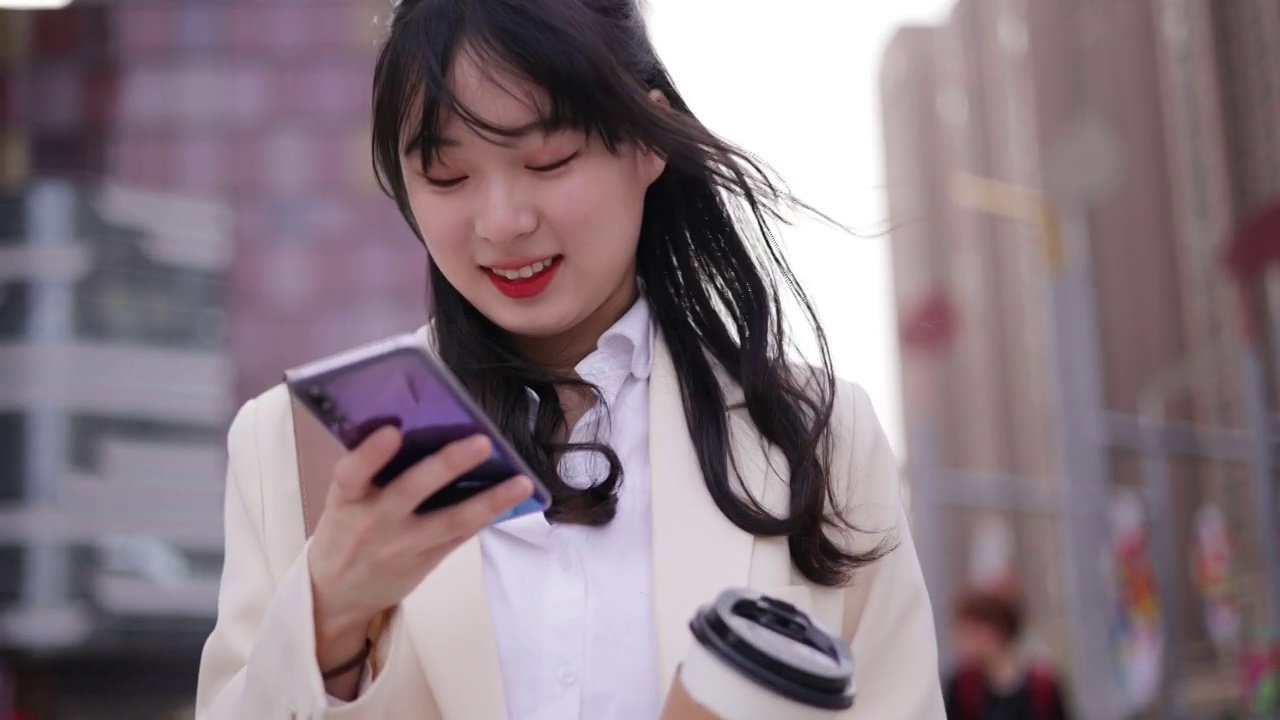 年轻的女孩用手机站在城市街头视频素材
