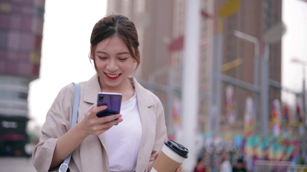 年轻的女孩用手机站在城市街头视频素材