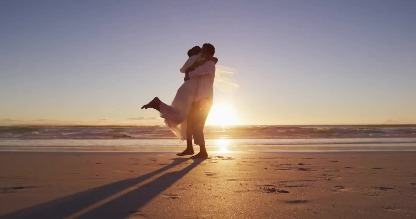 一对非裔美国情侣在夕阳西下的海滩上拥抱结婚视频下载