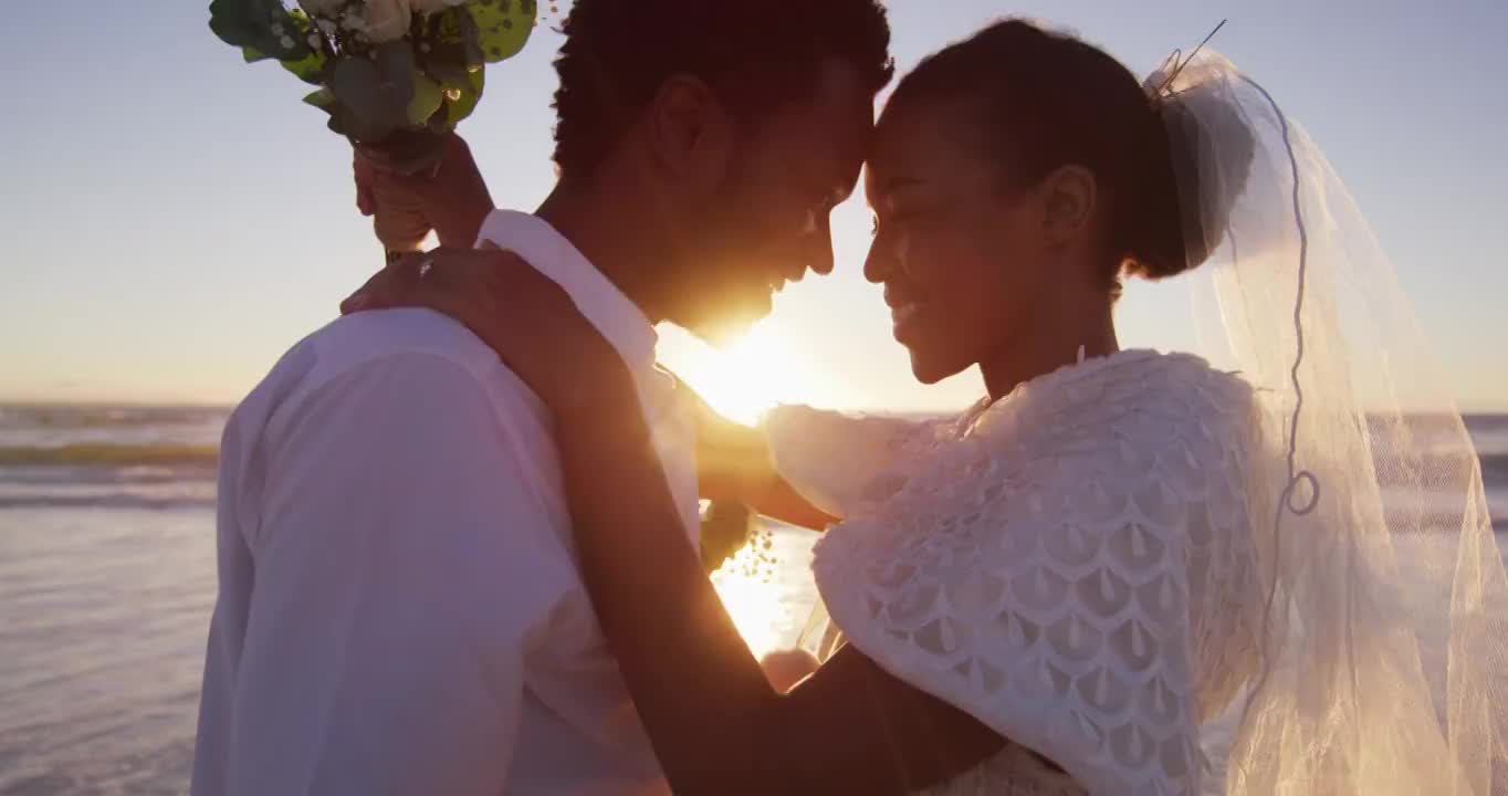 相爱的非裔美国人结婚了，在日落时分的海滩上看着对方视频下载