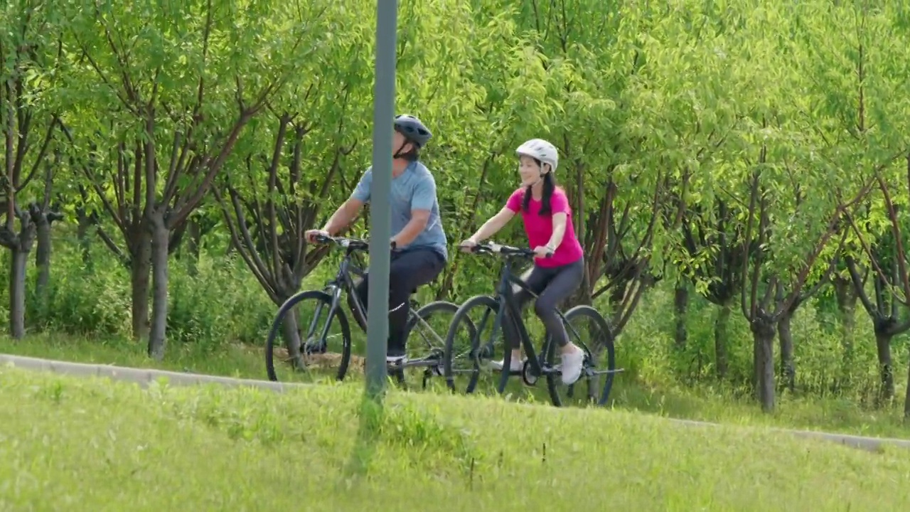 开心的中老年夫妇在公园骑自行车视频素材