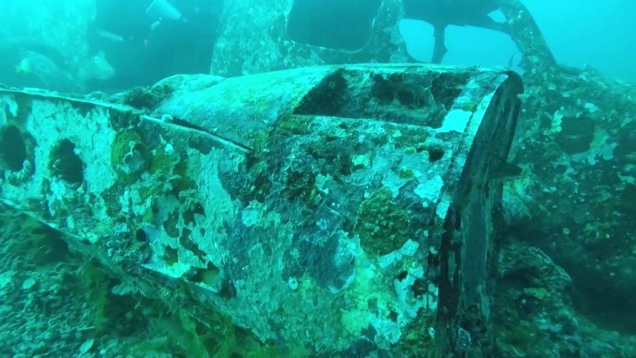 一个钻进水下飞机残骸的侧挂水肺潜水员视频素材