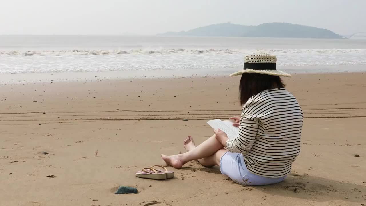 坐在海边沙滩看书的女人视频素材