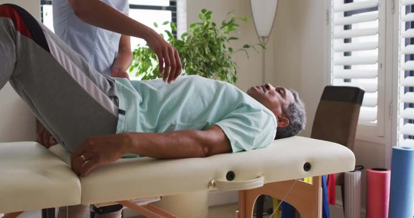 混血女理疗师帮助年长男子伸展双腿视频素材