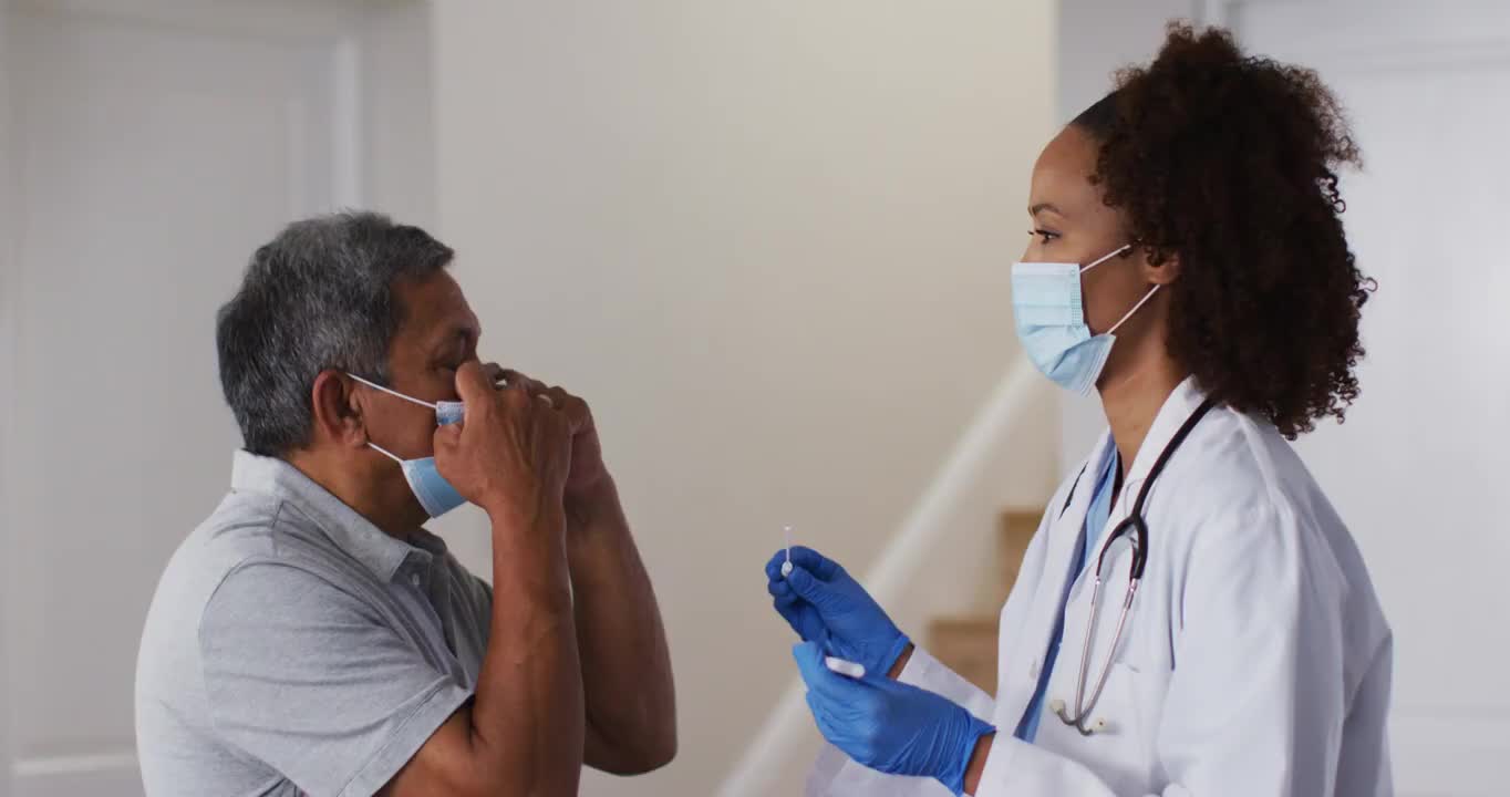 混血女医生戴着口罩在家中对老人做拭子测试视频素材