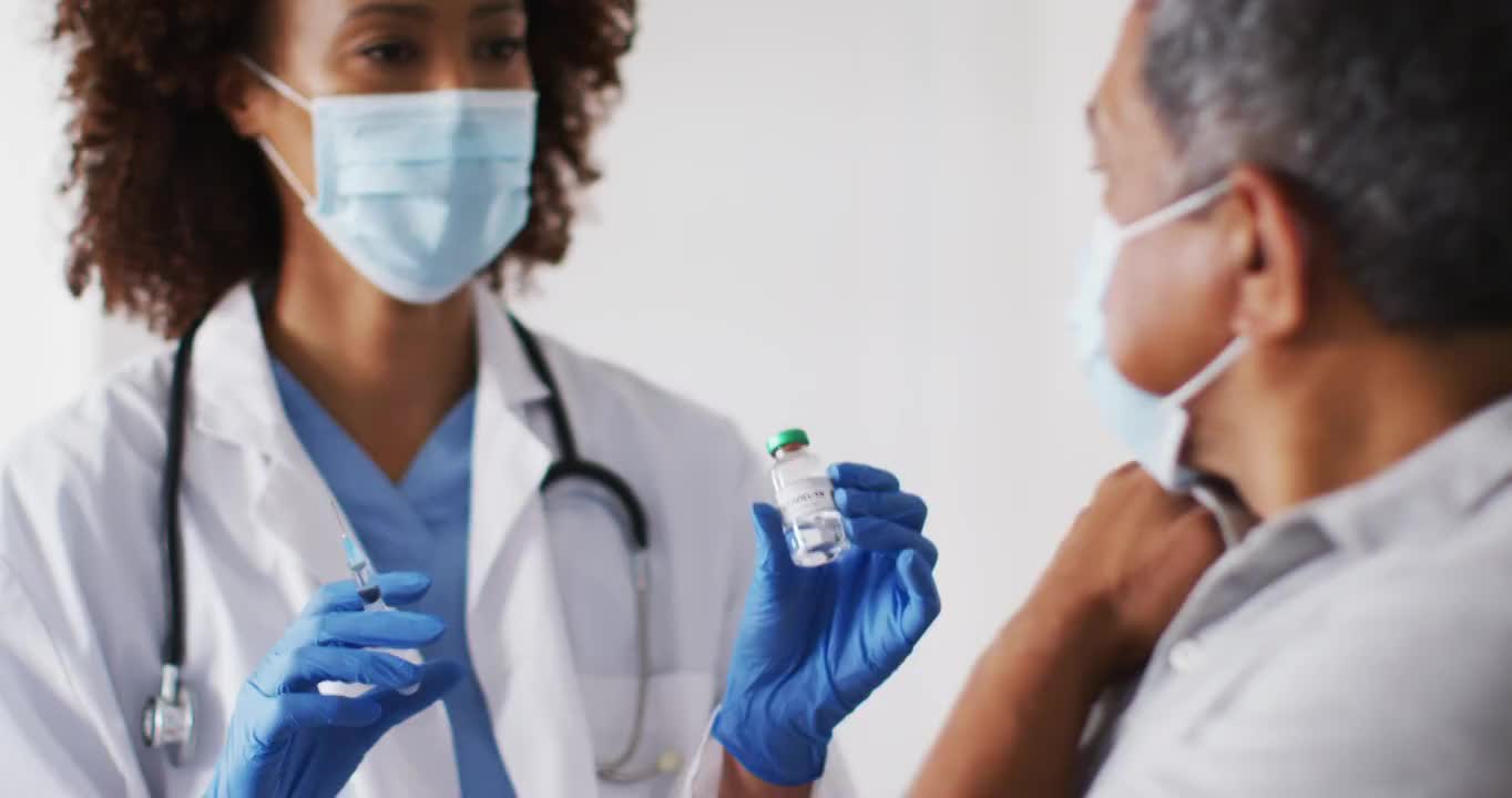 混血儿女医生戴着口罩在家给老人接种疫苗视频素材