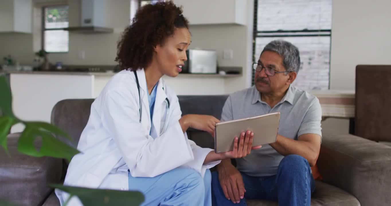 混血女医生和高级男子使用平板电脑和交谈视频素材