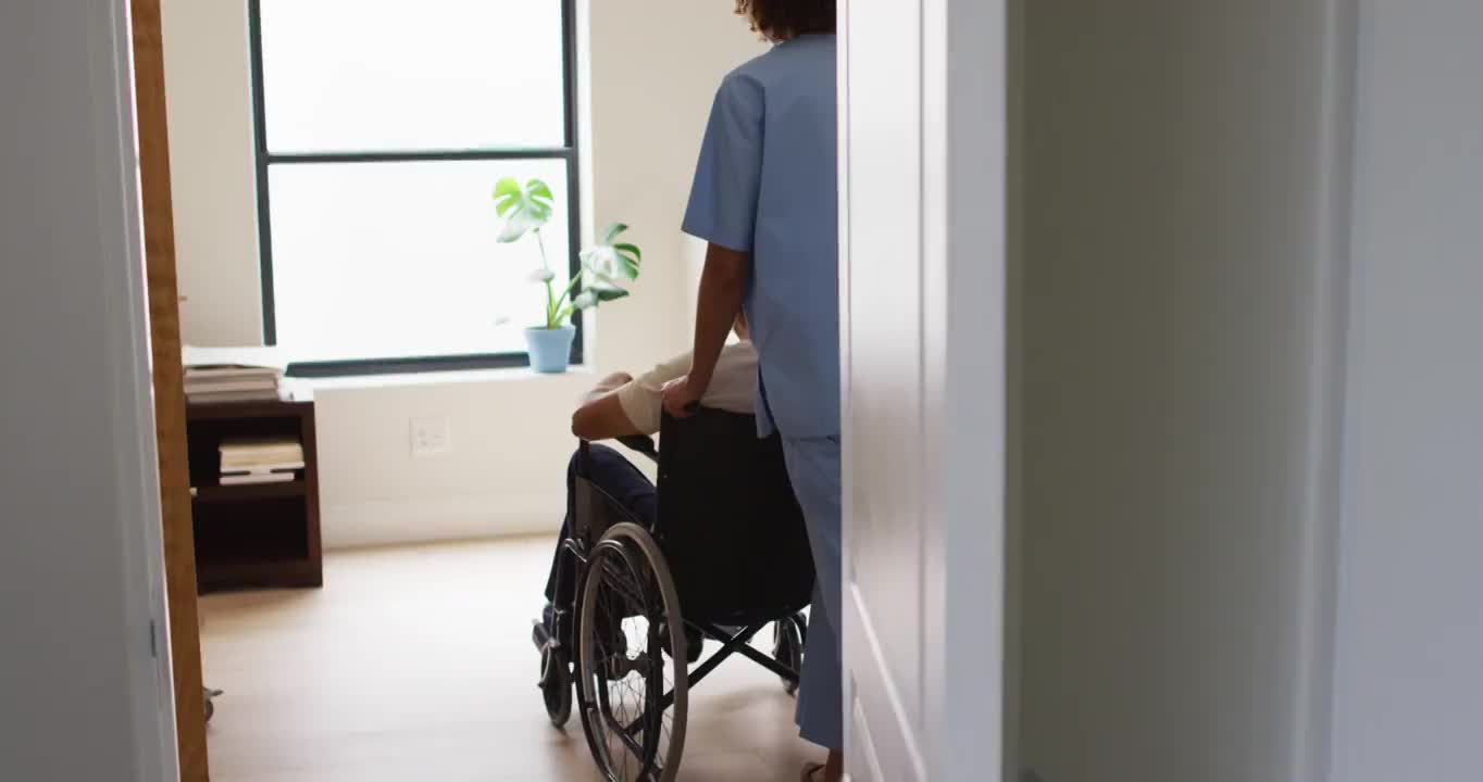 混血女医生在家里帮助坐在轮椅上的老人视频素材