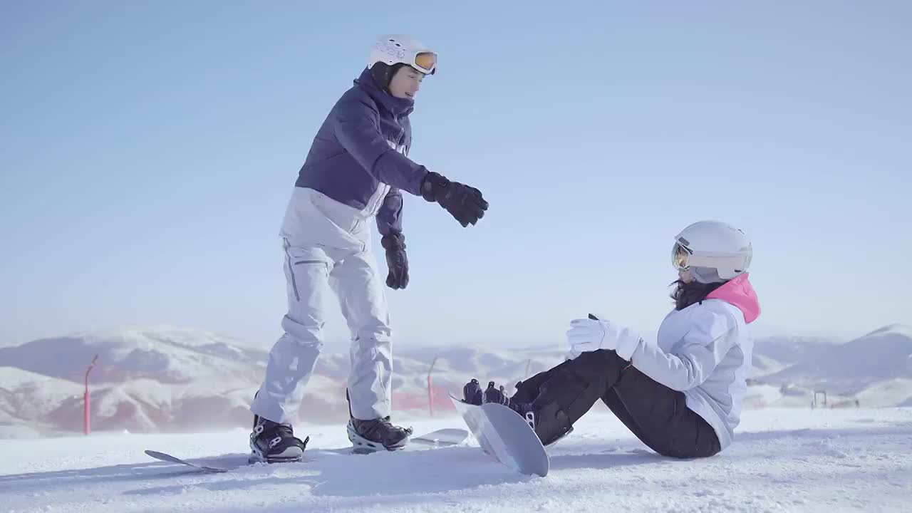 年轻男子教女朋友单板滑雪视频素材
