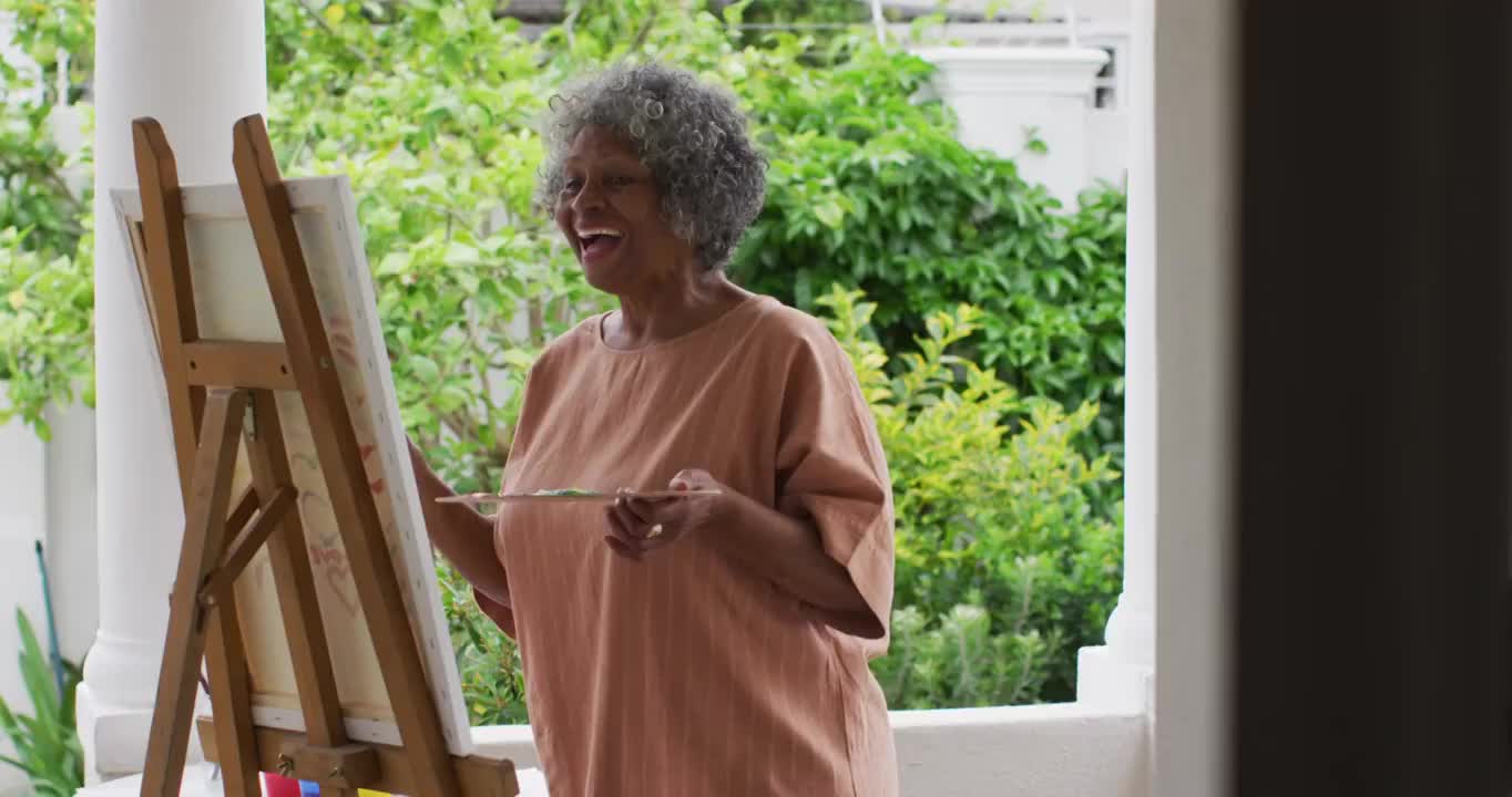 一位高级非洲裔美国妇女站在房子的门廊上作画视频素材