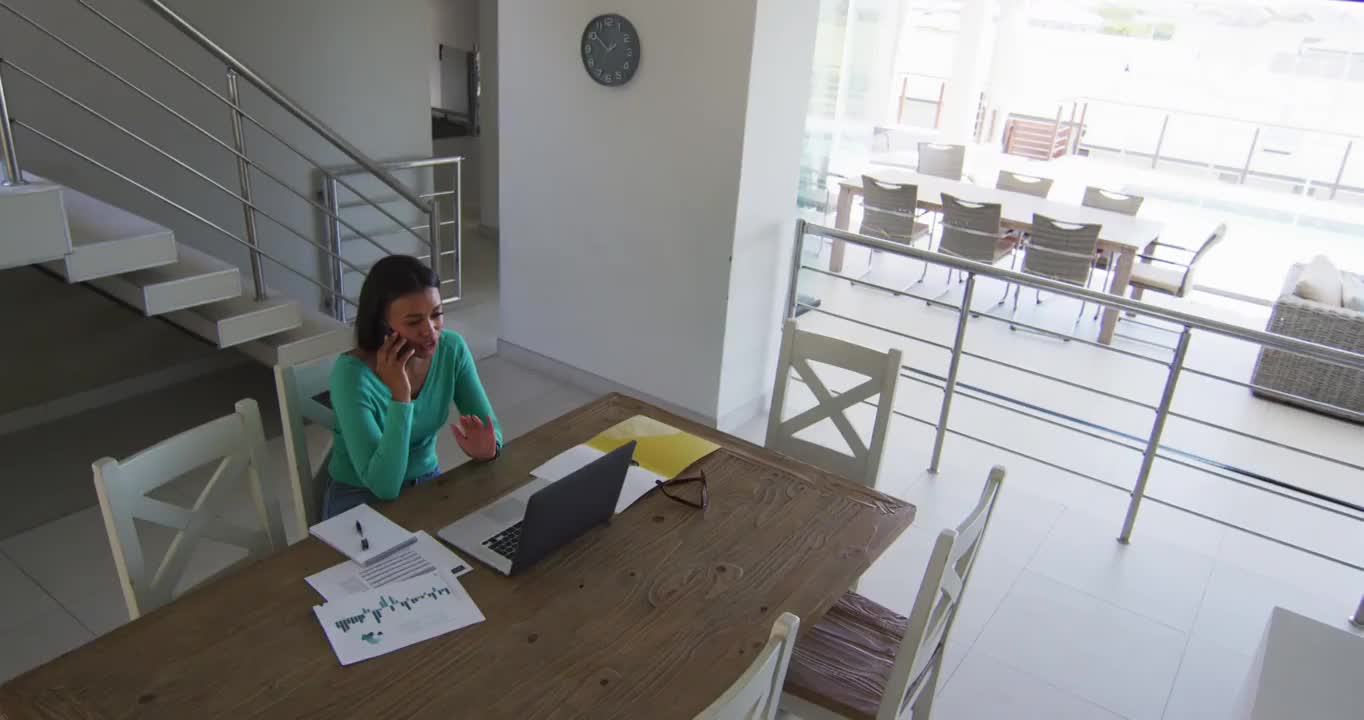 一位非裔美国妇女在家里用智能手机和笔记本电脑聊天视频素材