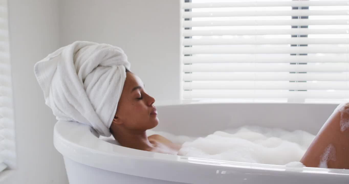 非裔美国妇女在家浴室的浴缸中放松视频素材