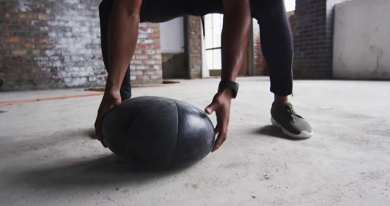 一个非裔美国人在一个空的城市建筑里用实心球锻炼视频素材