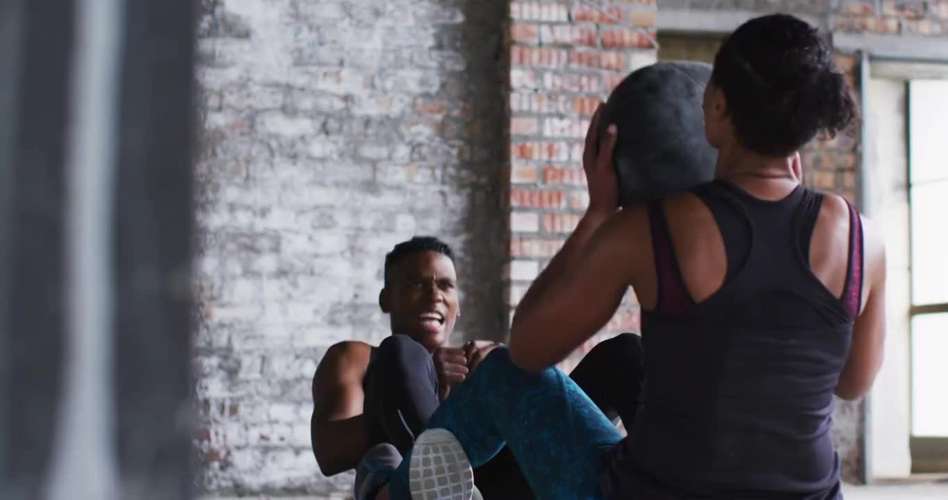 非裔美国男人和女人在一个空的城市建筑练习实心球视频素材