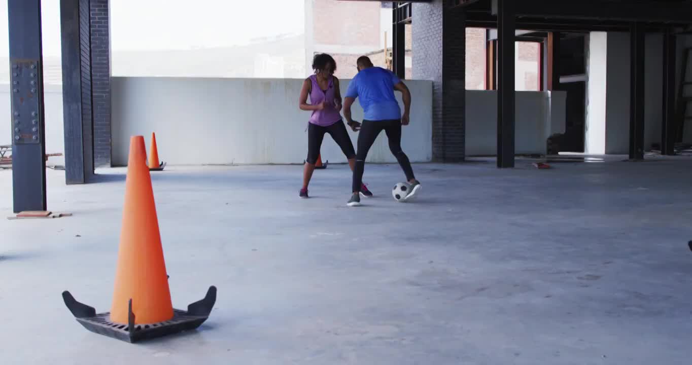 非裔美国人在一座空的城市建筑里踢足球视频素材
