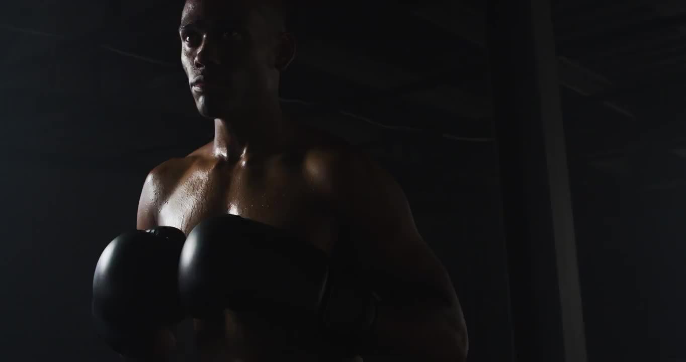 一个非裔美国人戴着拳击手套，在黑暗的房间里紧握拳头视频素材