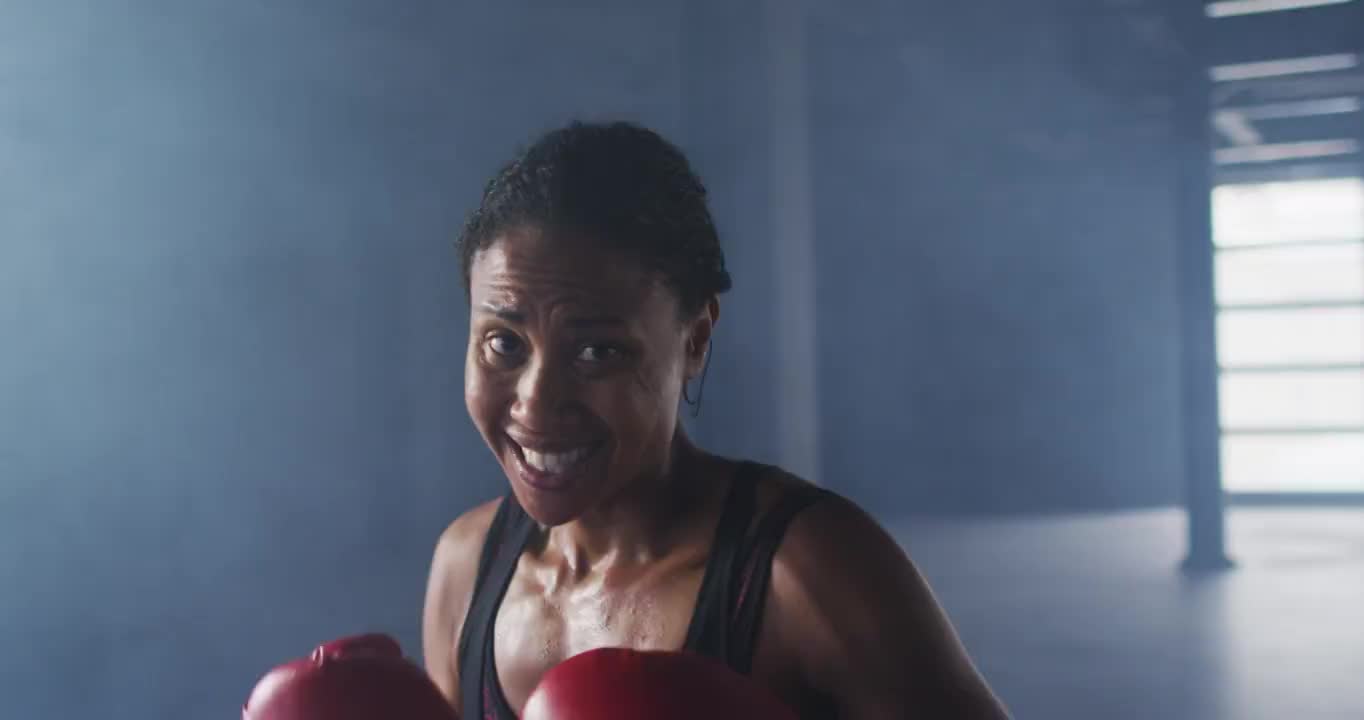 非洲裔美国妇女戴着拳击手套在空房间里训练投掷拳头视频素材