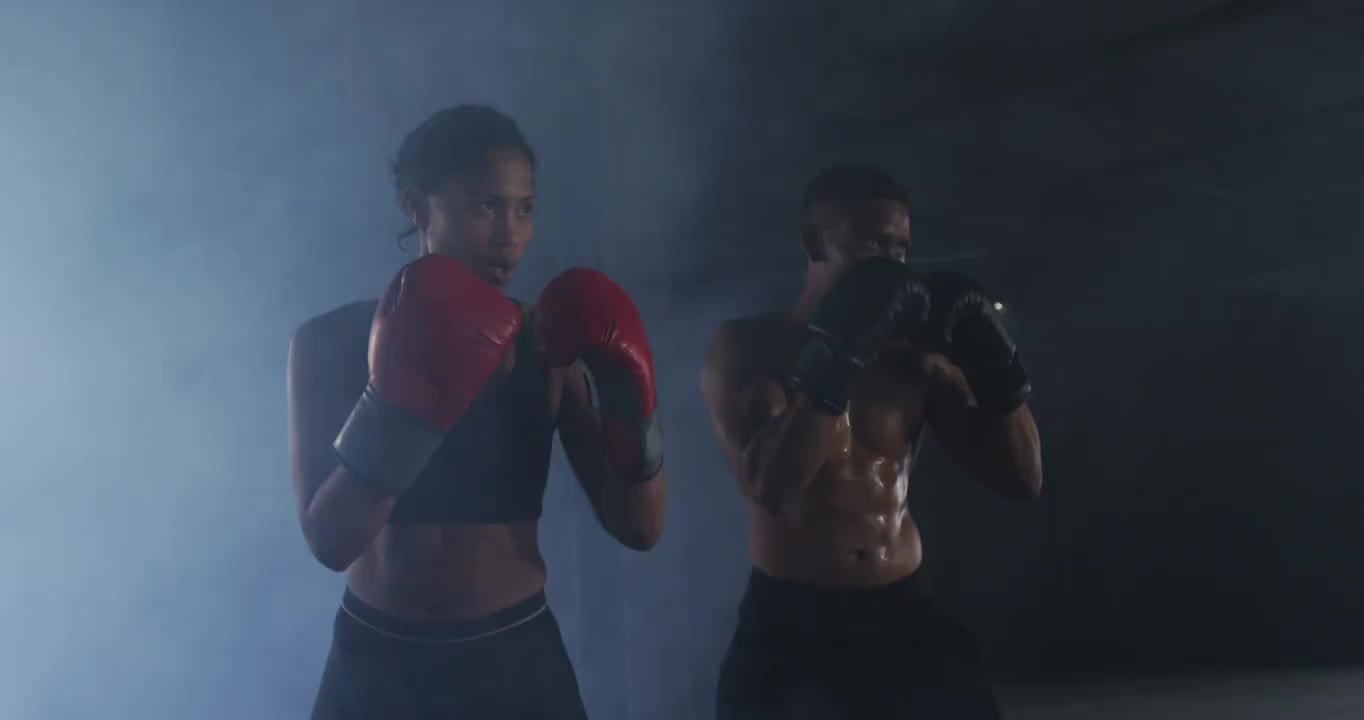 非洲裔美国男人和女人戴着拳击手套在空房间里训练投掷拳头视频素材