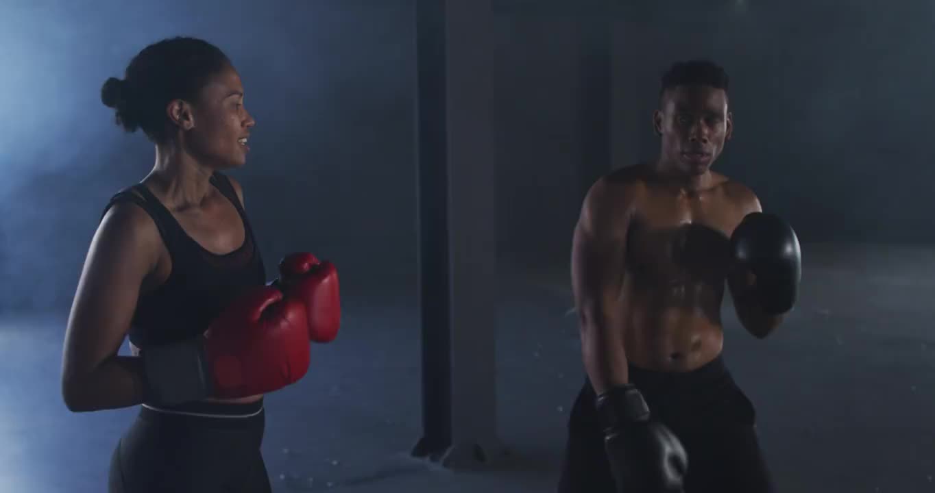 非洲裔美国男人和女人戴着拳击手套在空房间里训练投掷拳头视频下载