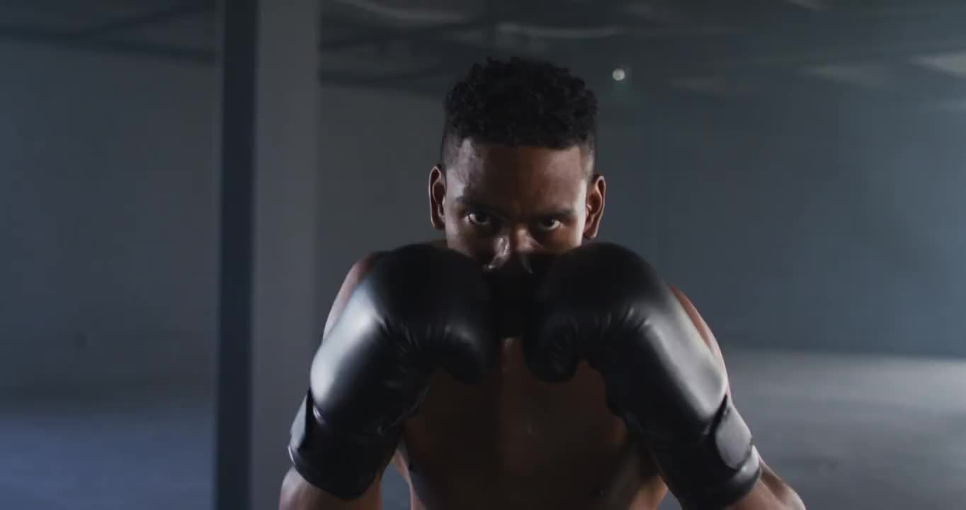 非洲裔美国人戴着拳击手套在空房间里训练投掷拳头视频下载