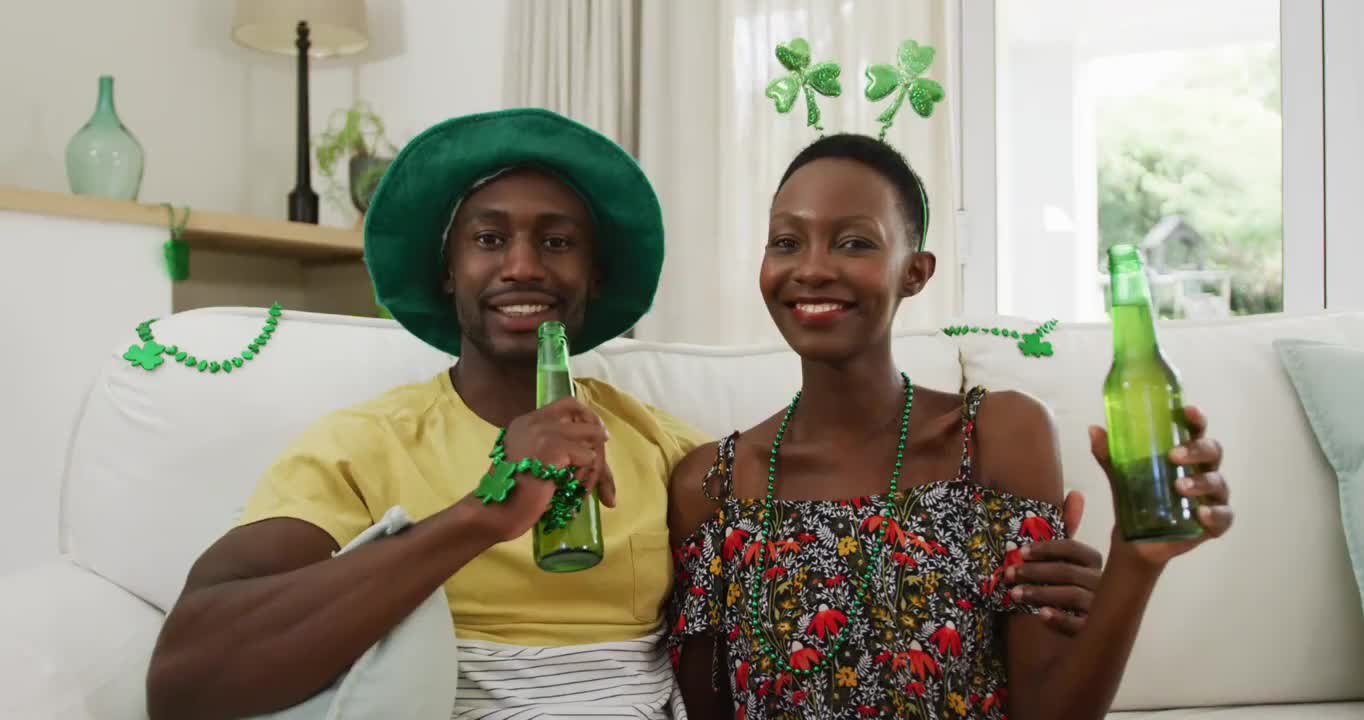 肖像的非洲裔美国夫妇在圣帕特里克节的帽子拿着啤酒微笑着对着镜头视频素材