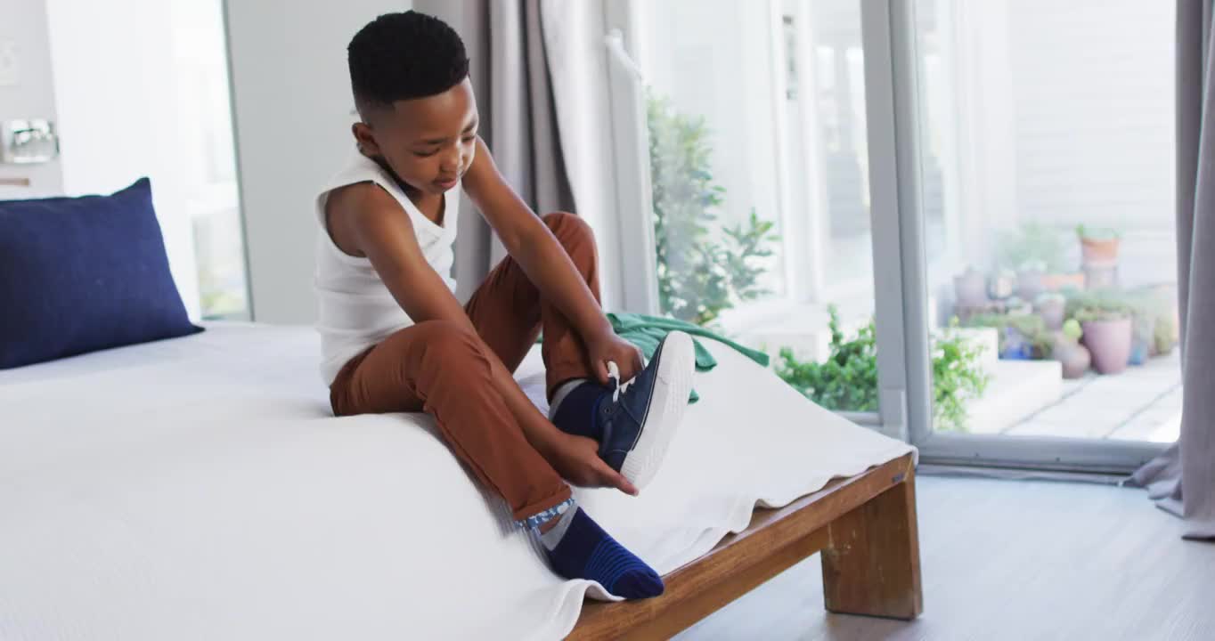 一个非裔美国男孩站在卧室里换衣服视频素材