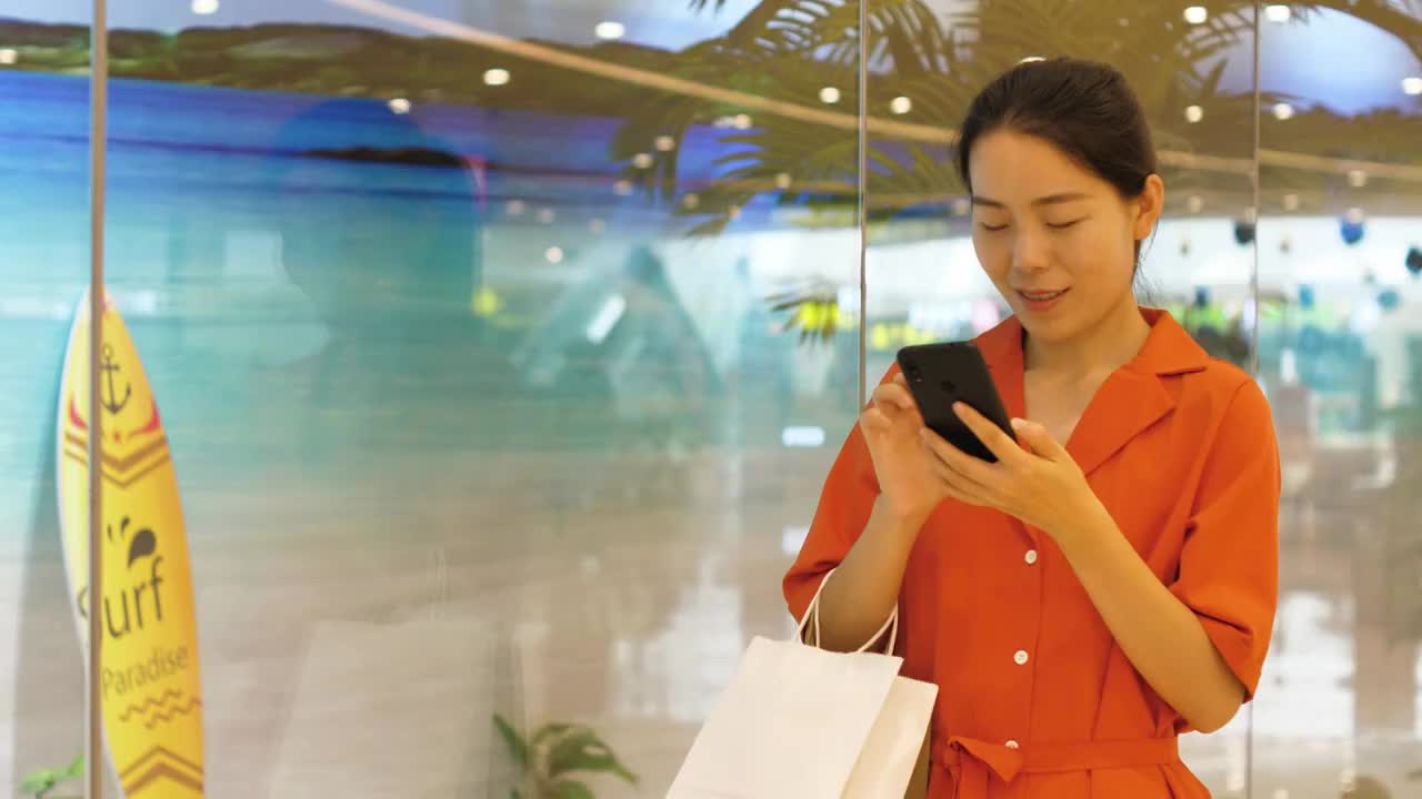 4k高清视频亚洲中国女性在商场玩手机互联网沟通视频素材