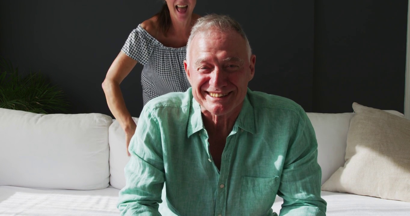 幸福的白人老年夫妇肖像微笑和交谈，同时有一个视频电话在家里视频素材