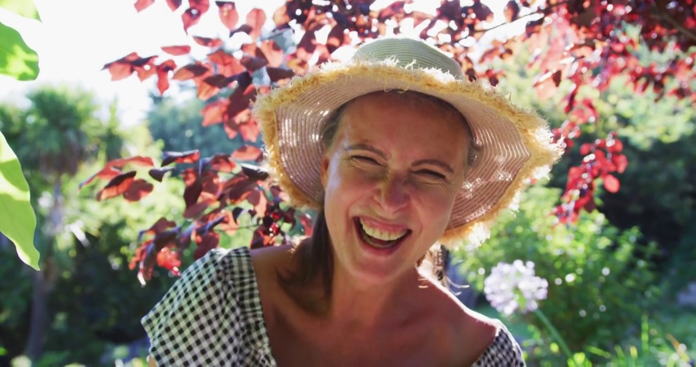幸福的白人老年妇女的肖像在花园里戴着太阳帽和在阳光下微笑视频素材