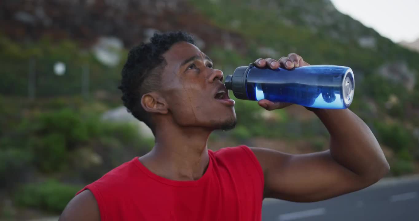一个非裔美国人站在路上喝水视频素材