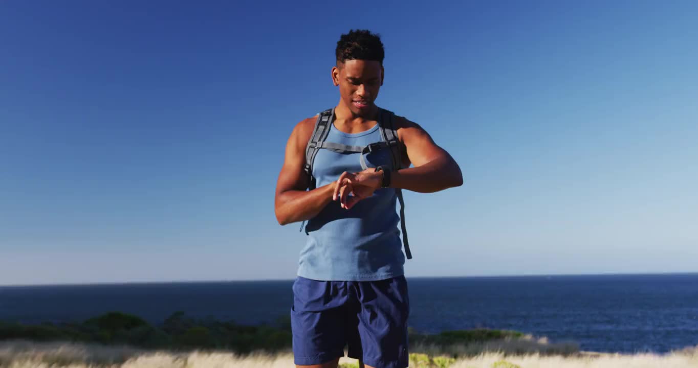 一名非裔美国男子在乡村山区使用智能手表越野跑步视频素材