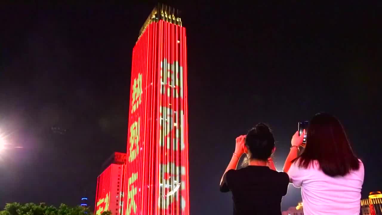广西南宁市行人用手机记录建党百年灯光秀视频素材