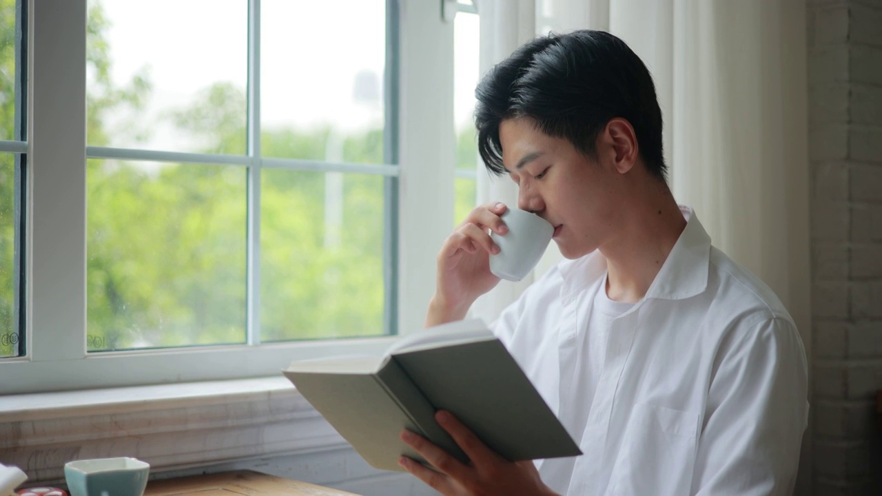 年轻男人在窗前阅读视频下载
