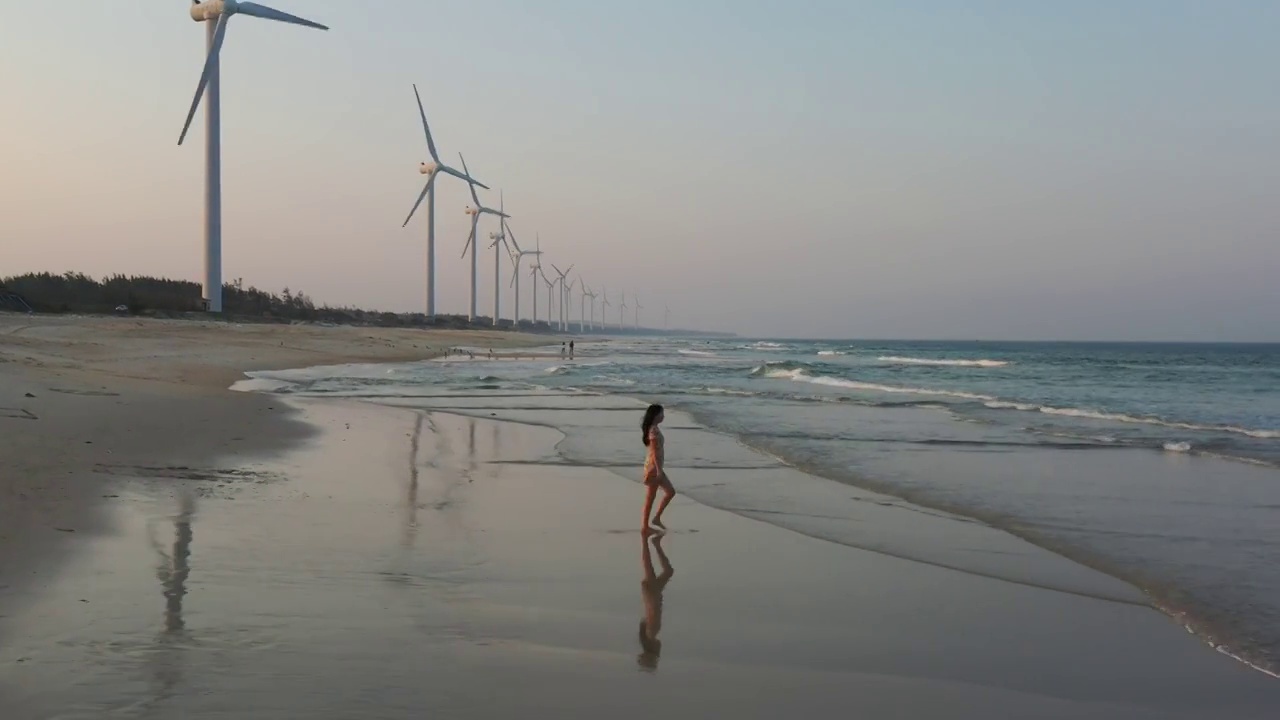 航拍海南文昌海岸沙滩风力发电机少女海滩行走视频素材